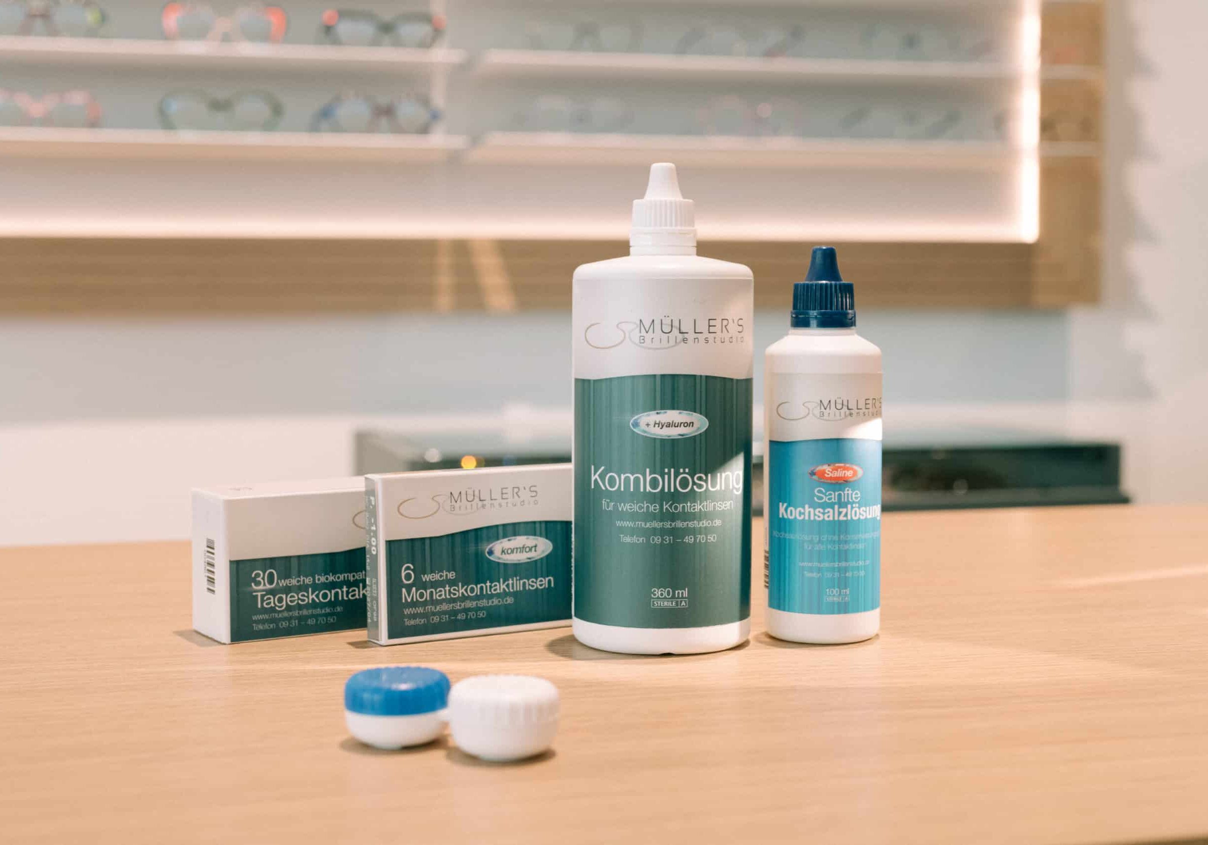 Kontaktlinsen-Pflegeprodukte von Müllers Brillenstudio – Kombilösung, Kochsalzlösung, Tages- und Monatskontaktlinsen auf Ladentheke.