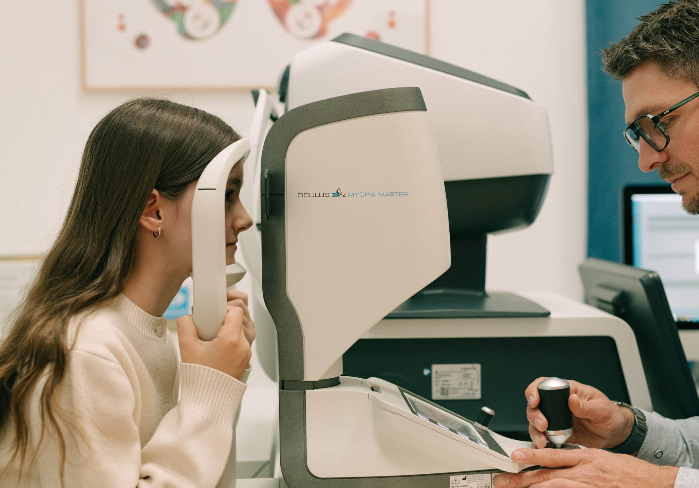 Junges Mädchen sitzt beim Optiker vor dem Gerät Myopia Master für das Myopie Management.